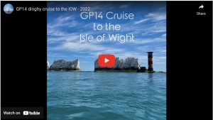 Blue sky, chalk islands and a lighthouse across a calm sea on a sunny day.