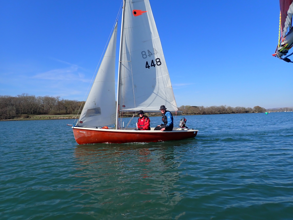 Two people in a sailing dinghy on a sunny day